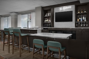 A modern kitchen with a bar area, bar stools, a flat-screen TV, and a wine rack. - Hampton Inn Ft. Lauderdale/Downtown Las Olas Area (Fort Lauderdale)