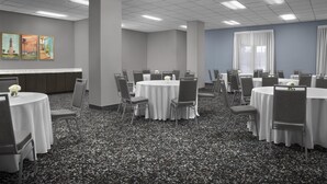 A conference room with round tables, chairs, and a carpeted floor.