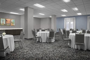 A conference room with round tables, chairs, and a carpeted floor.