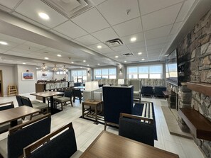 A spacious hotel lobby with multiple seating areas, a reception desk, and large windows offering views.