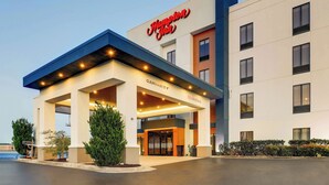 A Hampton Inn hotel with a clear entrance, a covered area with lights, and a sign indicating a clearance of 12 feet 9 inches.