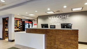 A reception desk with a "Welcome to the Peach State" sign, a HP monitor, and a Hilton logo.