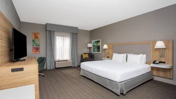 Ein Hotelzimmer mit einem großen Bett, einem Flachbildfernseher, einem Schreibtisch und einem Sessel.