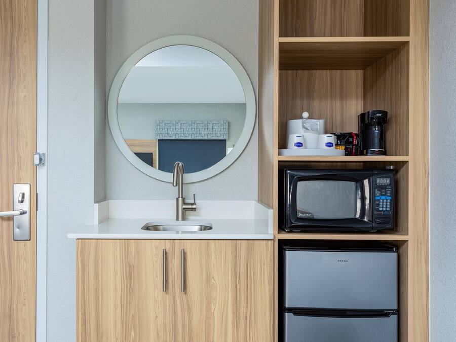 Une petite cuisine équipée d’un évier, d’un four à micro-ondes et d’un petit réfrigérateur.