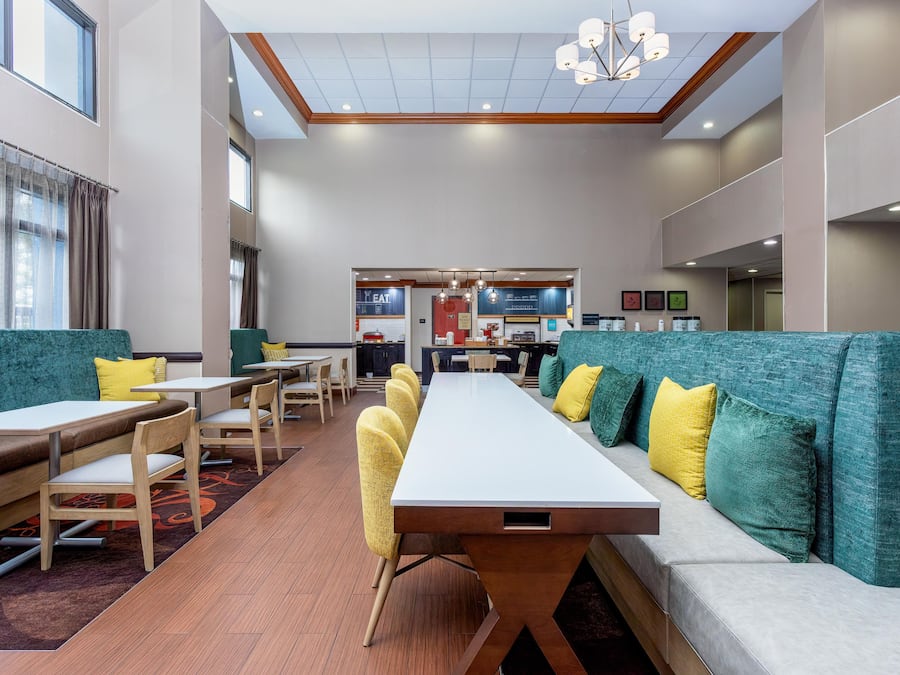 A modern hotel dining area with high tables, booths, and a central kitchen area.
