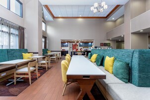 Un comedor de hotel moderno con mesas altas, cabinas y una zona central de cocina.