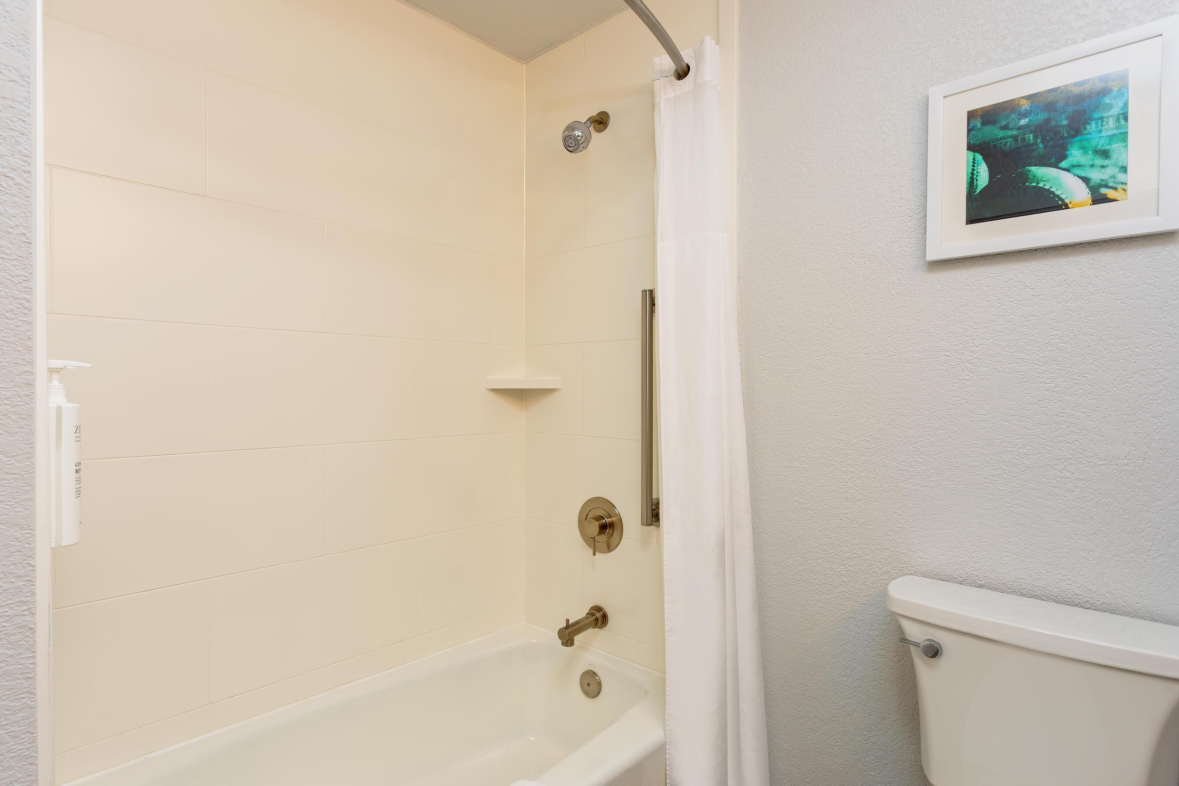 Une salle de bain avec une baignoire, des toilettes et un tableau encadré au mur.