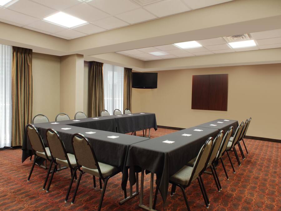 Un salón de conferencias con una larga mesa, sillas, un televisor de pantalla plana y un panel de madera en la pared.