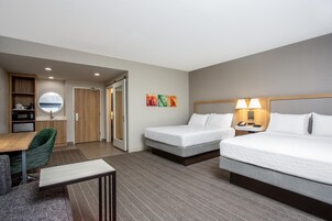 Une chambre d’hôtel avec deux lits, un bureau, une chaise, une petite kitchenette et une salle de bain.