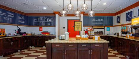 A kitchen with a central island, wooden cabinets, and a checkered floor.
