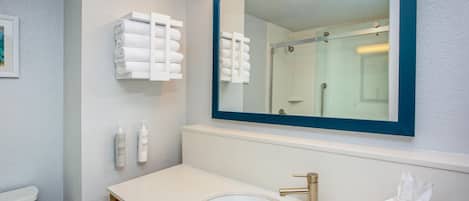 A bathroom with a white sink, a large mirror, and a towel rack.