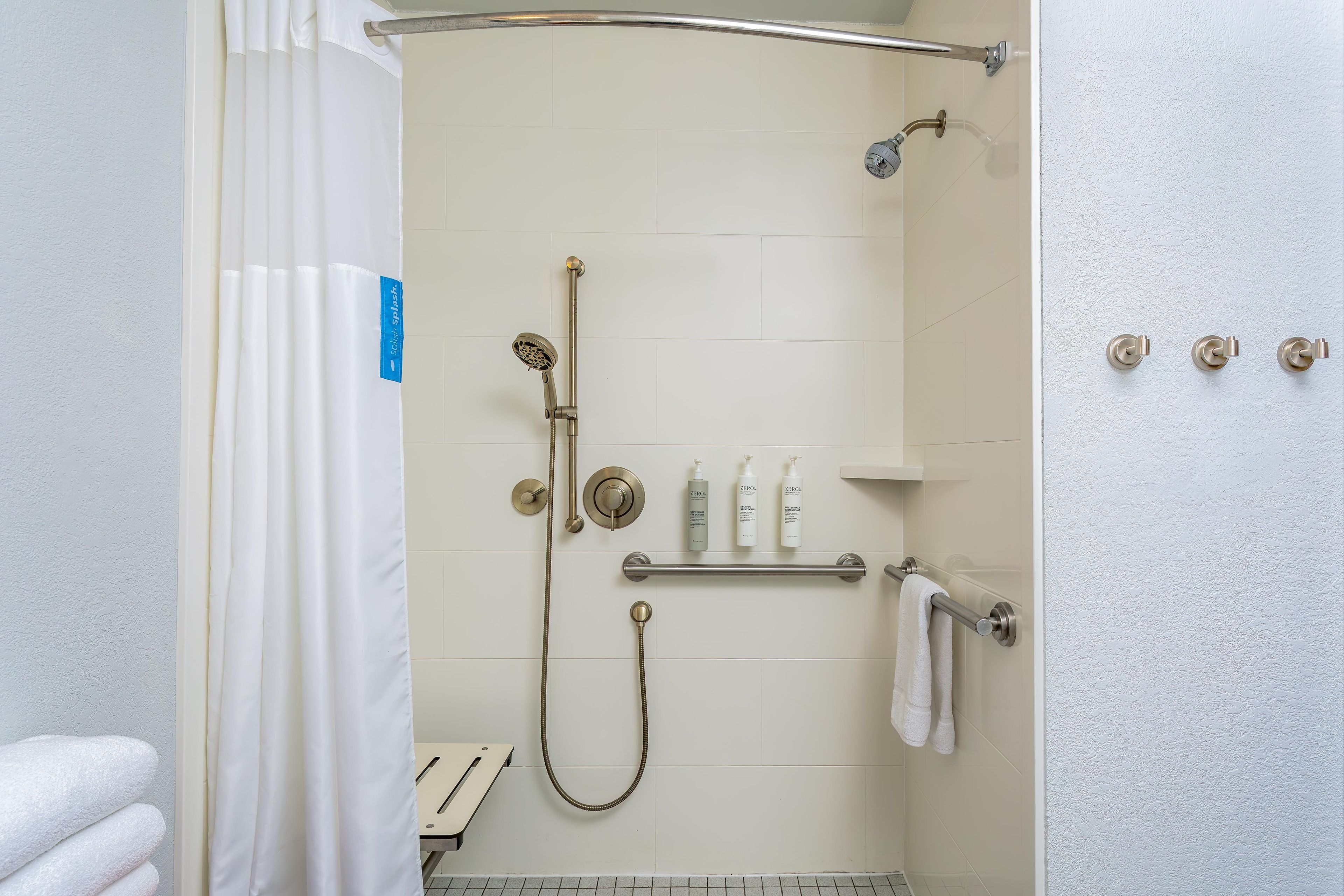 A shower area with a handheld showerhead, a wall-mounted faucet, and a towel rack with a towel.
