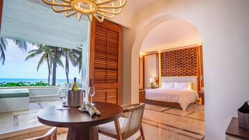 A hotel room with a bed, a bedside table, a lamp, and a view of the ocean.