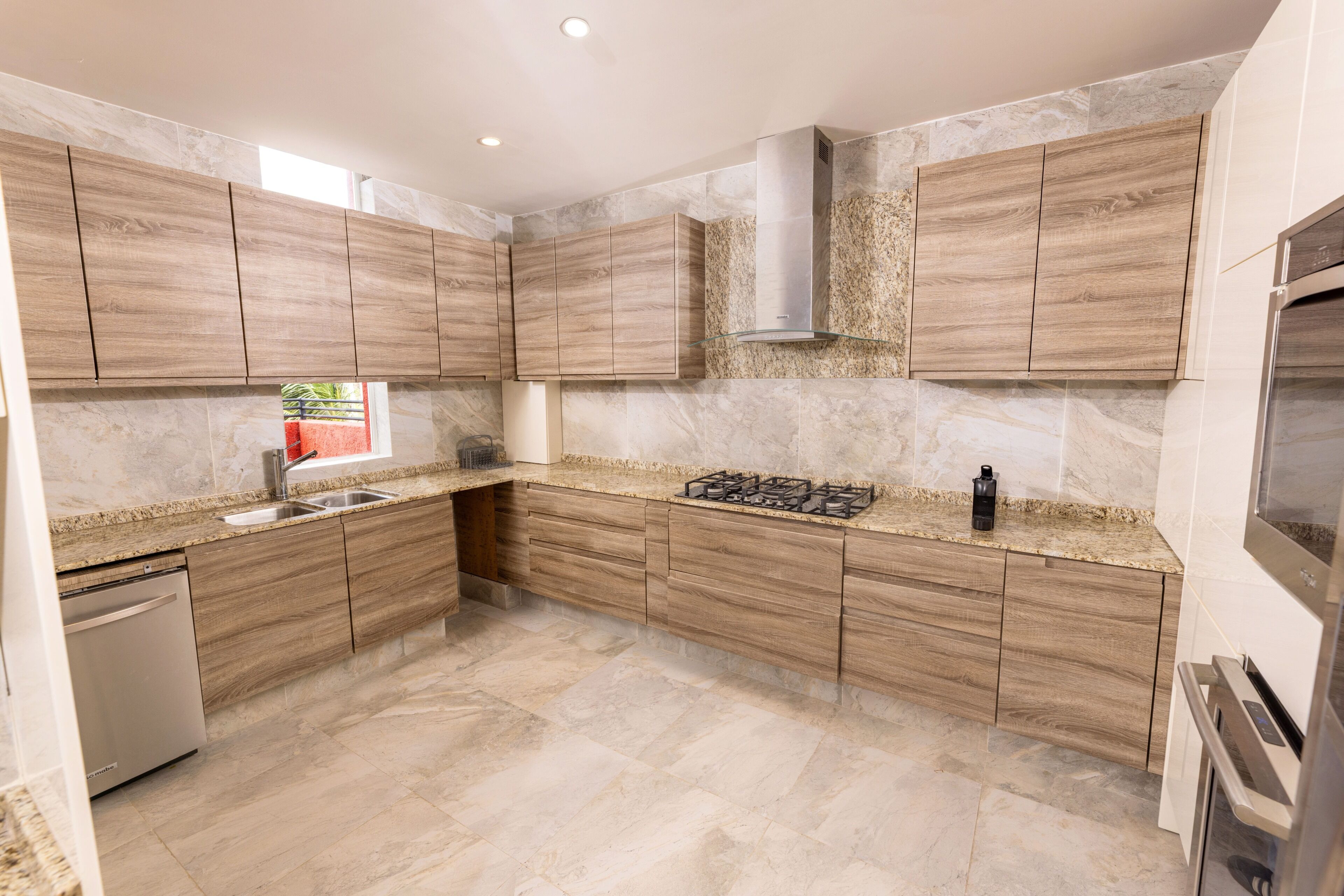 A modern kitchen with wooden cabinets, a stainless steel range hood, and a built-in dishwasher.