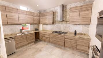 A modern kitchen with wooden cabinets, a stainless steel range hood, and a built-in dishwasher.