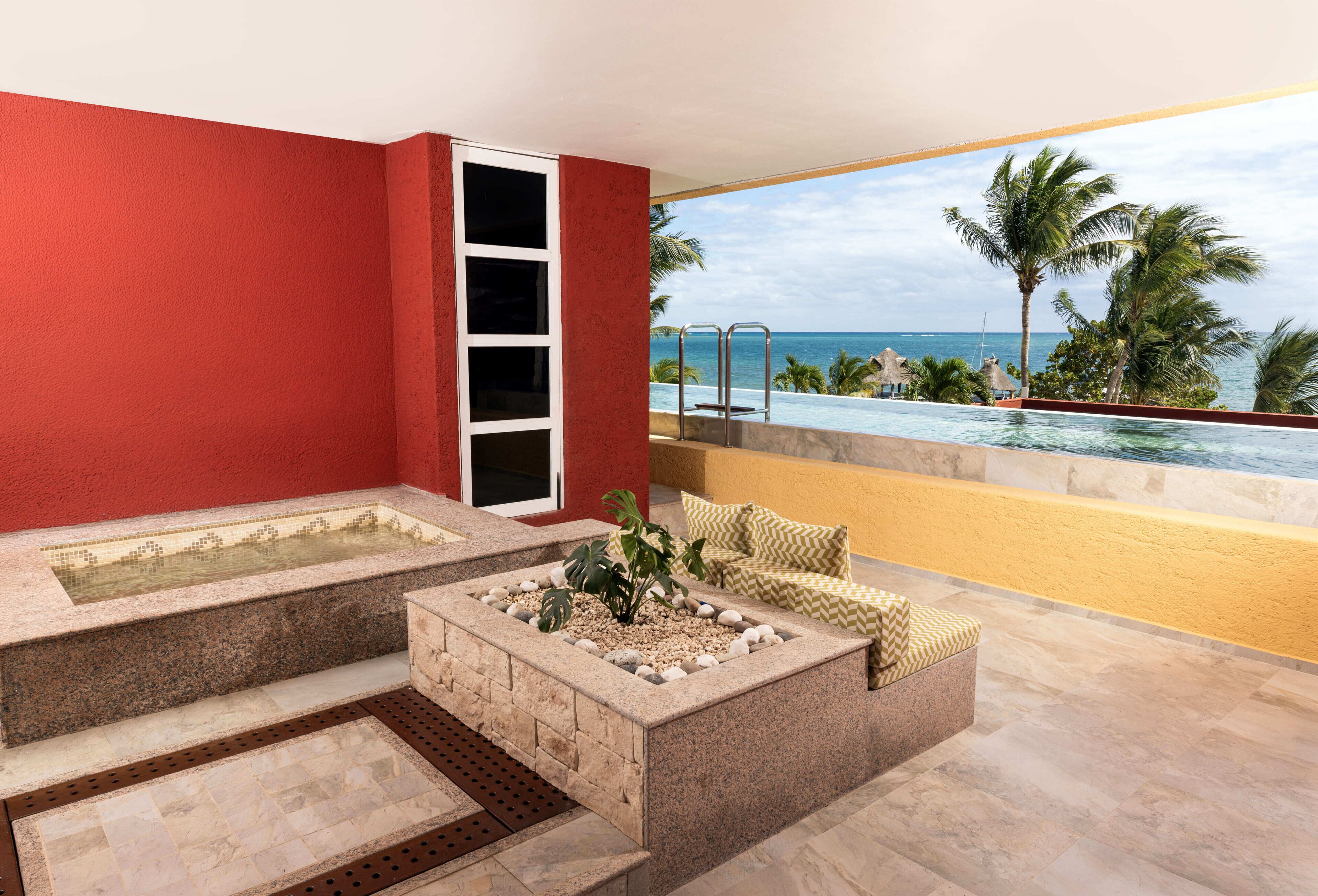 A spa area with a hot tub, a seating area with cushions, and a view of the ocean.