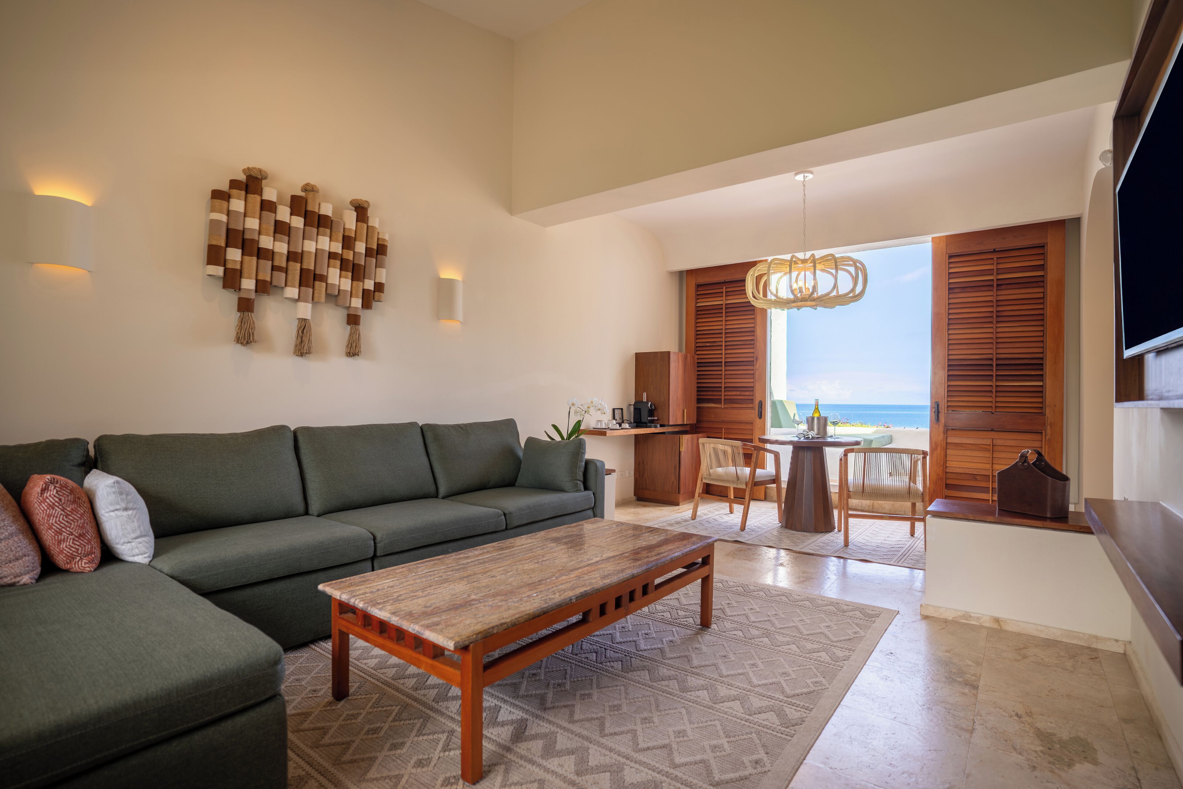 A living room with a sofa, a coffee table, and a view of the beach through large windows.