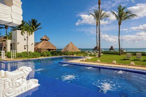 Ein Pool mit einem Zierbrunnen, einer strohgedeckten Konstruktion und Blick auf das Meer.
