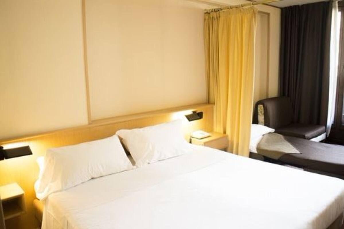 Une chambre d’hôtel avec un lit, une chaise, une table de chevet et une lampe.