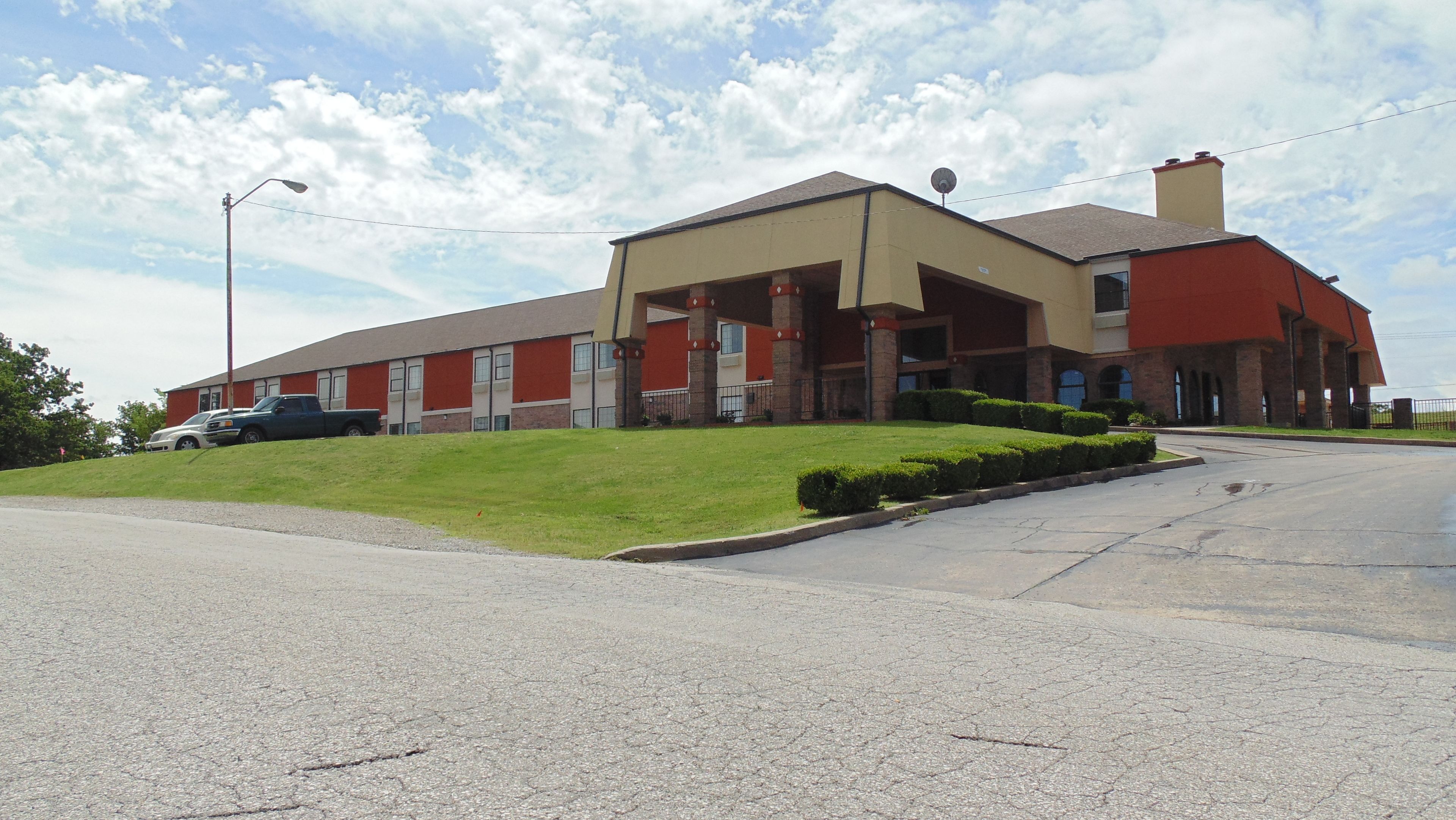 A two-story building with a flat roof, a red and beige color scheme, and a parking lot in front.