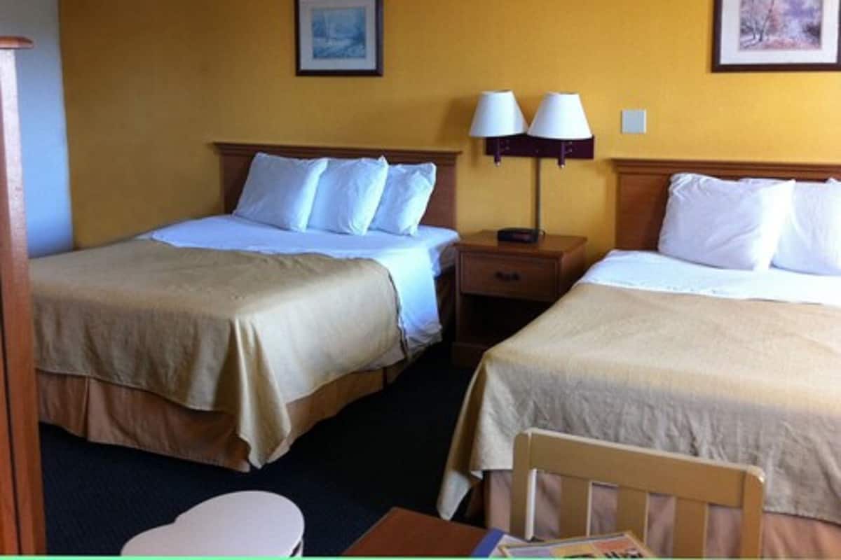 Une chambre d’hôtel avec deux lits, une table de chevet avec des lampes et deux tableaux encadrés au mur.