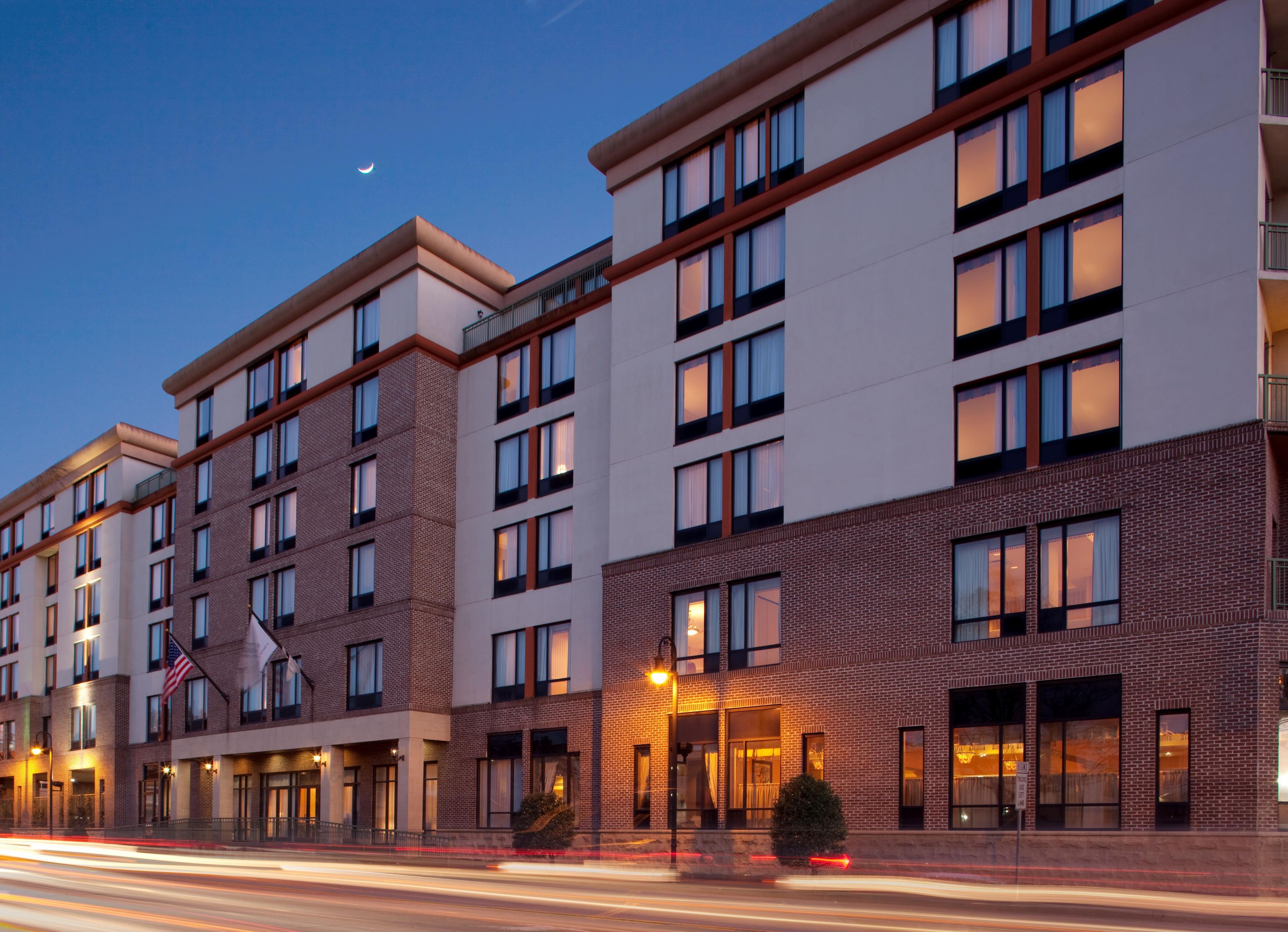 A multi-story hotel with a brick facade, large windows, and a flag.