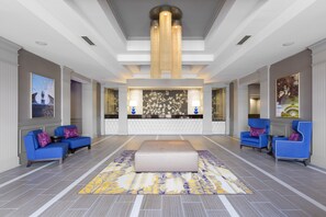 A spacious lobby with a central reception desk, blue armchairs, a patterned rug, and a chandelier. - DoubleTree by Hilton Hotel Savannah Historic District (Savannah)