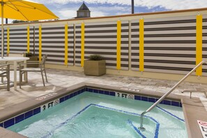 Un área de piscina con borde de azulejos, una banca y una mesa con sillas.