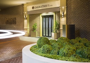 A DoubleTree by Hilton hotel entrance with a brick facade, double doors, and a landscaped garden area. - DoubleTree by Hilton Hotel Savannah Historic District (Savannah)