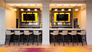 A bar area with two mirrored sections, each with a TV, bar stools, and a minibar. - DoubleTree by Hilton Hotel Savannah Historic District (Savannah)