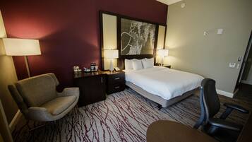 Une chambre d’hôtel comprenant un lit, deux tables de chevet avec des lampes, une chaise et un bureau.