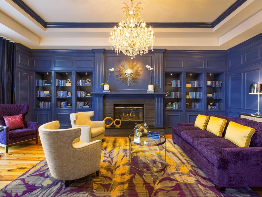 A room with a fireplace, bookshelves, a chandelier, and a patterned rug.