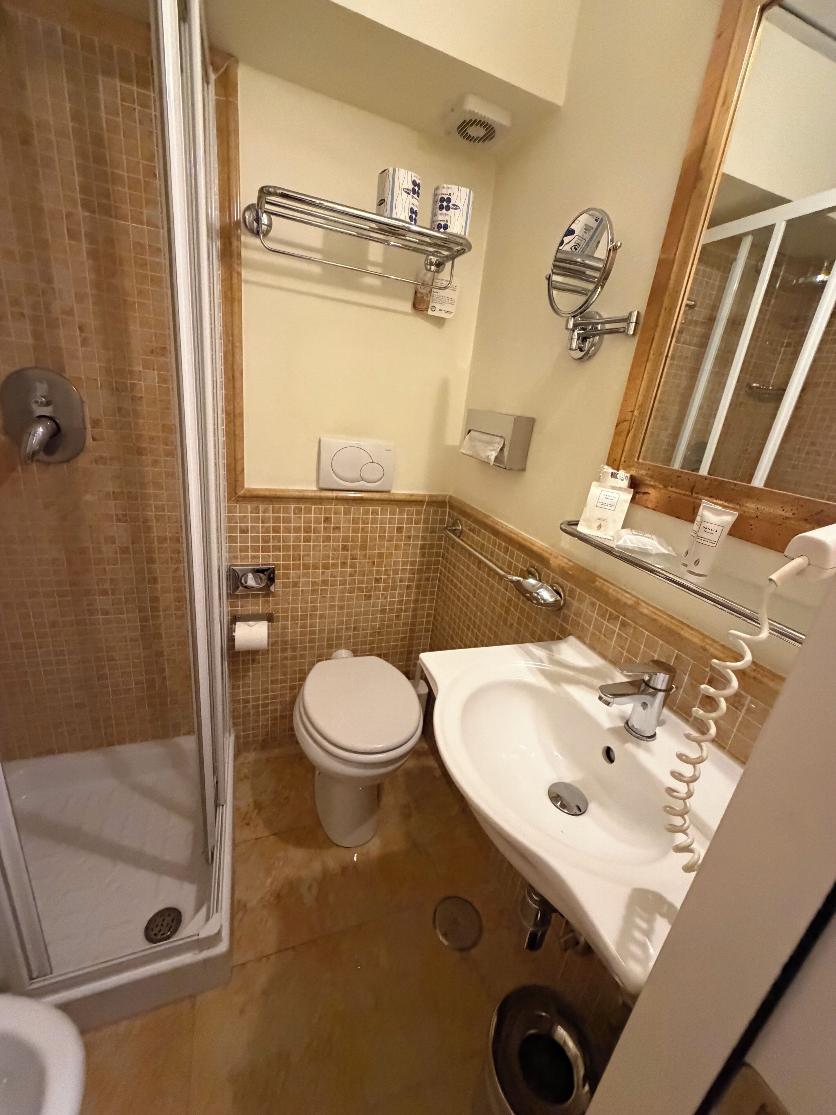 Une salle de bain équipée d’une douche, de toilettes, d’un lavabo et d’un miroir.