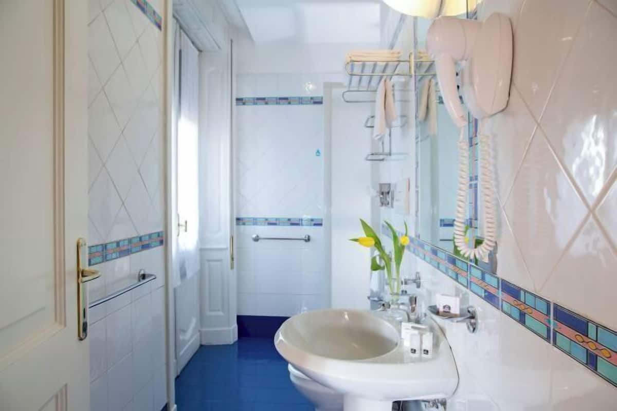 A bathroom with a white sink, a mirror, a towel rack, and a shower area.