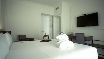 Habitación de hotel con una cama grande, televisor montado en la pared, escritorio con silla y minibar.