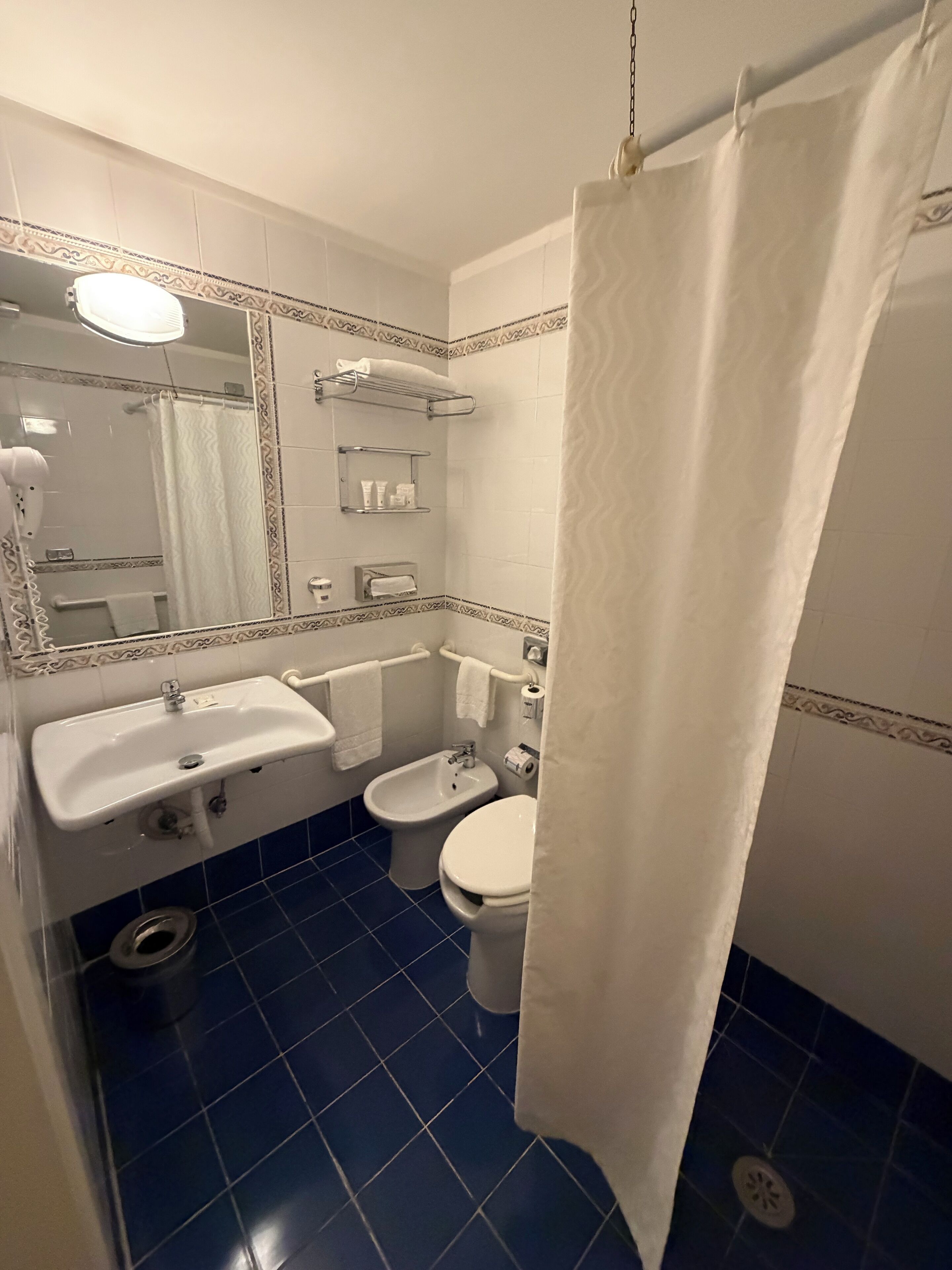 Un bany amb un lavabo, vàter, i cortina de banyera.