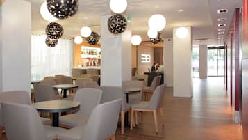 Um café moderno com mesas e cadeiras redondas, um espaço de bar e chão de madeira.
