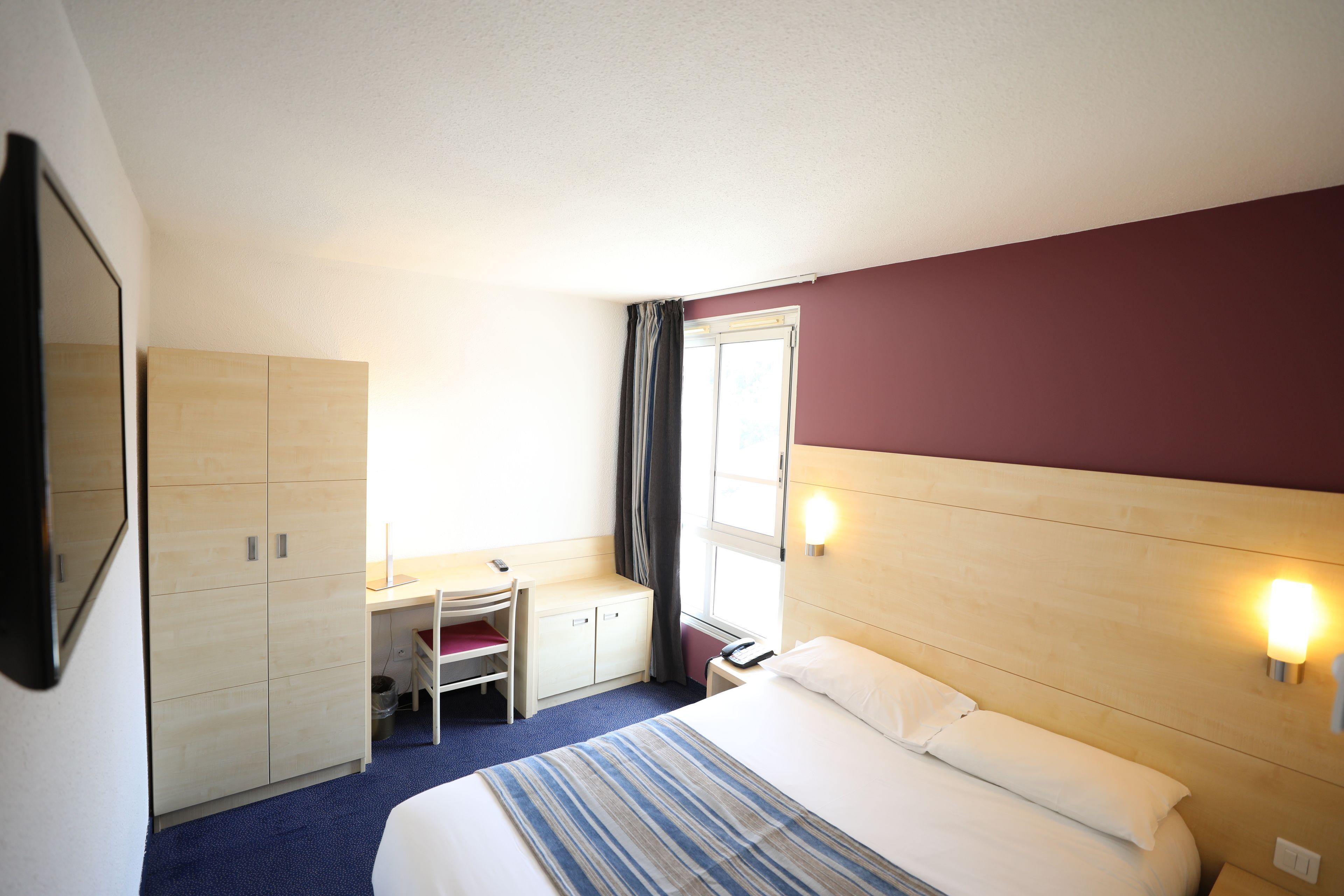 Una habitación de hotel con una cama, un escritorio y un armario.