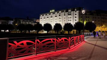 A hotel with a prominent 'ALBA' sign, a red decorative fence, and a paved walkway.