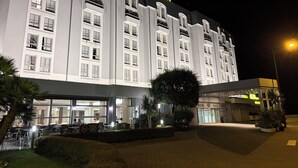 Et hotel med flere etager, et tydeligt 'ALBA'-skilt, store vinduer og et godt oplyst indgangsparti.
