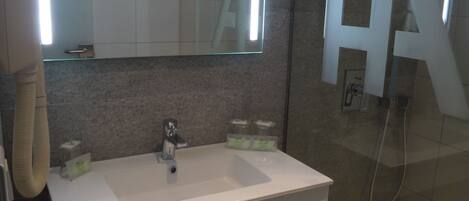 A modern bathroom with a large mirror, a sink, and a shower area.
