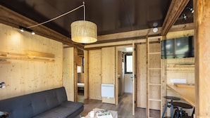 A cozy room with a sofa, a coffee table with fruit and a mug, a TV, and a wooden interior. - Camping de Paris (Paris)