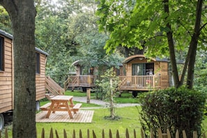 A wooden cabin with a deck and a picnic table in a wooded area.