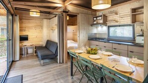 A modern interior with a wooden dining area, a sofa, and a kitchen with a stove and shelves. - Camping de Paris (Paris)
