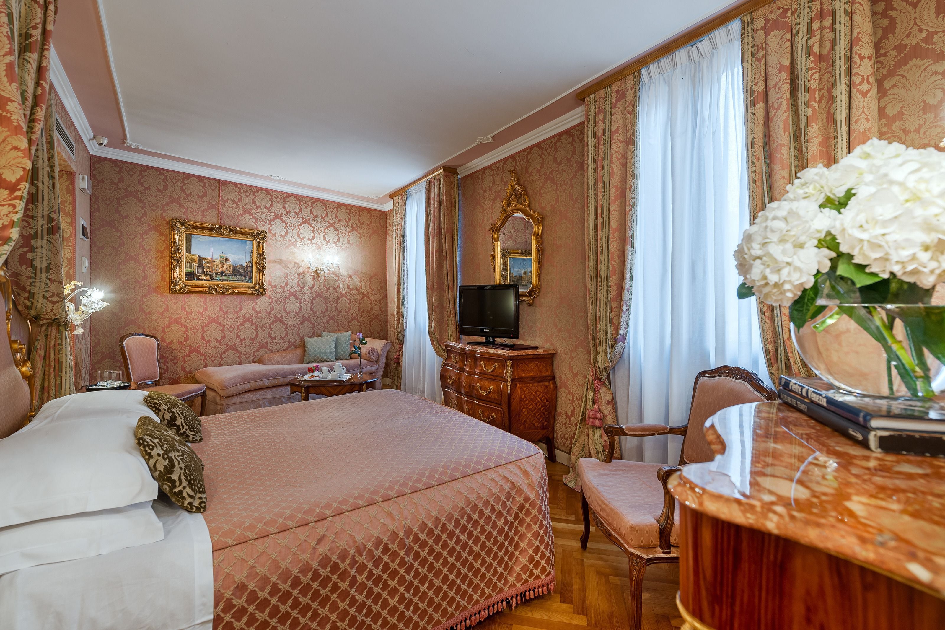 A hotel room with a large bed, a dresser, a television, and a mirror.