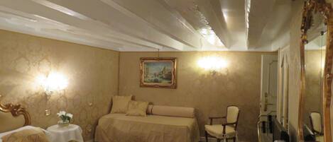 Habitación de hotel con dos camas, una silla, una mesa, un espejo y un cuadro en la pared.