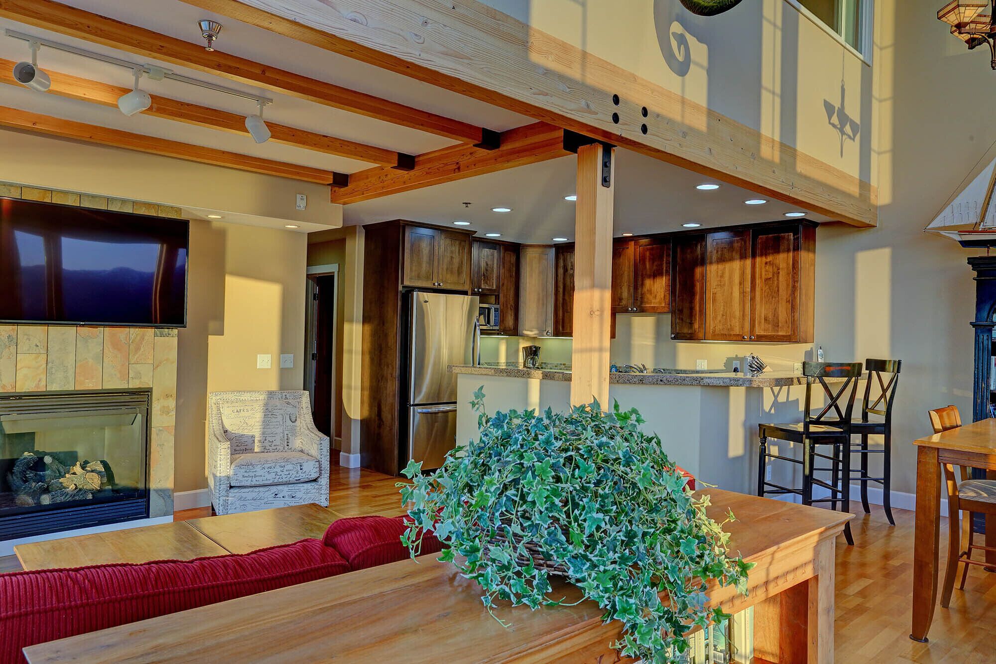 A modern kitchen with wooden cabinets, a built-in refrigerator, and a dining area with a wooden table and chairs.