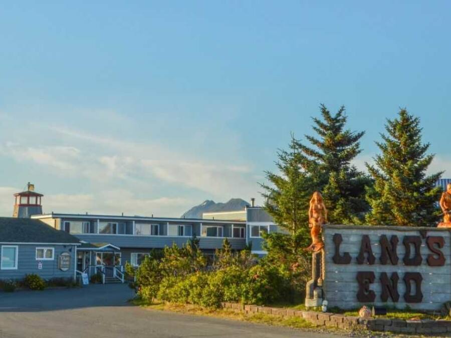 Um edifício com uma placa que diz "LANDS END" e um farol ao fundo.