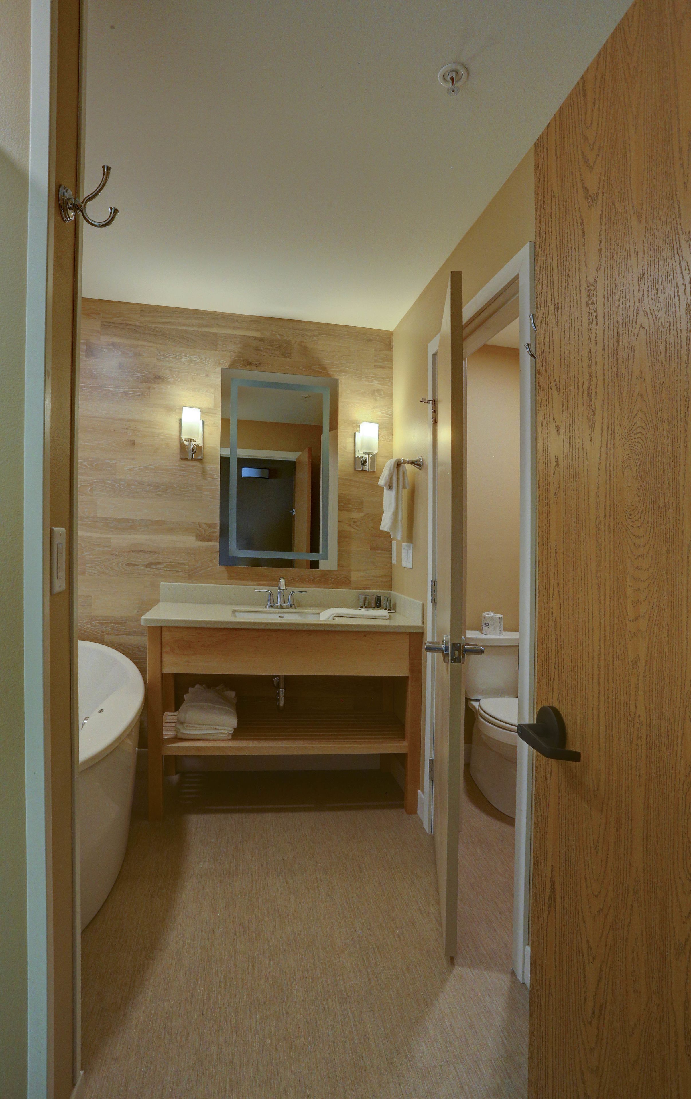 Une salle de bain avec un meuble-lavabo en bois, un évier, un miroir et des toilettes.