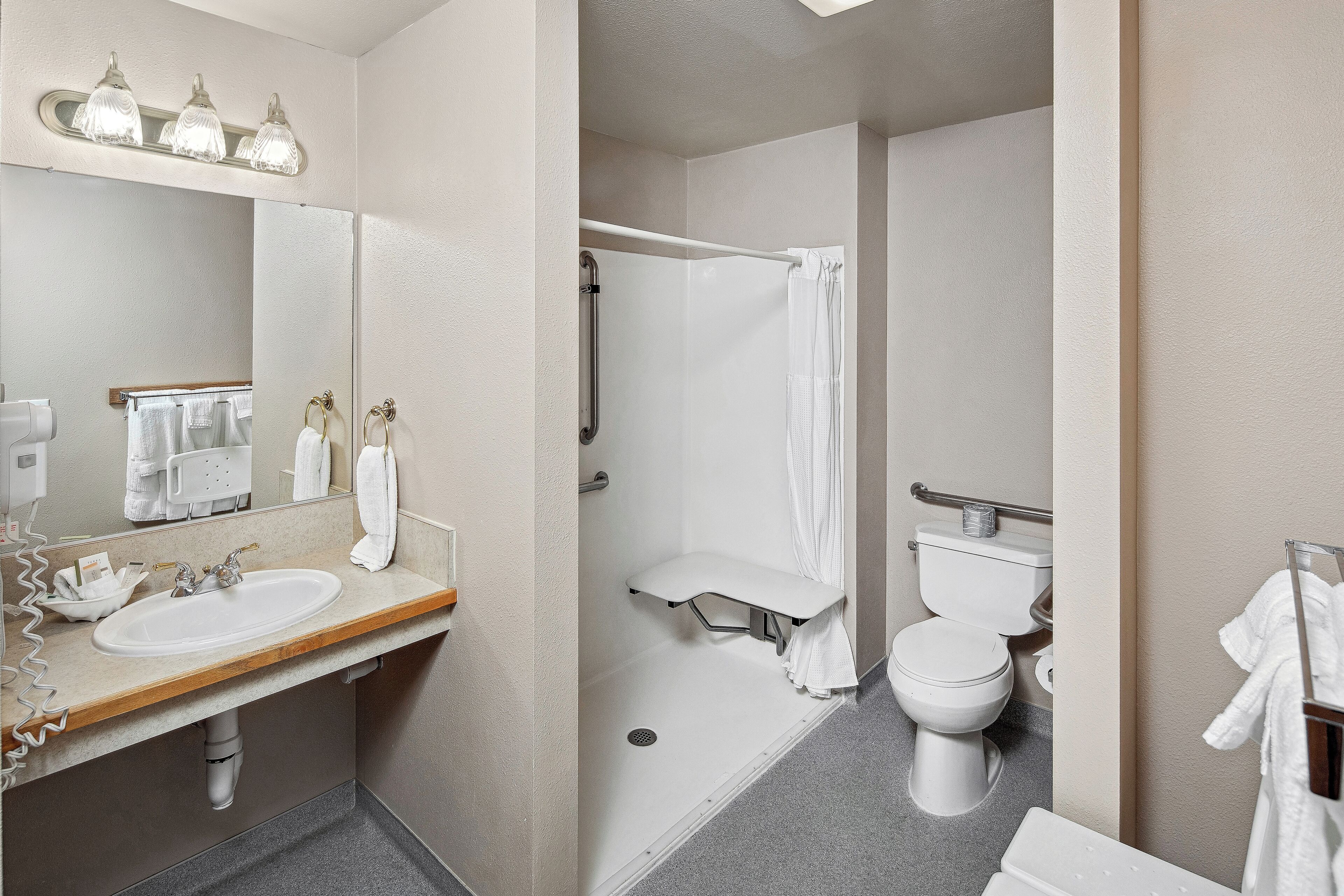 A bathroom with a sink, mirror, shower, and toilet.